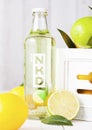 LONDON, UK - APRIL 27, 2018: Glass bottle of NKD alcoholic cocktail drink on wooden background with fresh lemons and limes Royalty Free Stock Photo