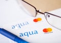 LONDON, UK - AUGUST 18, 2018: Aqua master card statement with glasses and blue pen.