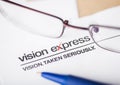 LONDON, UK - AUGUST 18, 2018: Vision Express Logo on papre with glasses and blue pen