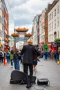 02/05/2019 London, UK. Busker playing on guitar on busy streets in Chinatown district in Soho.