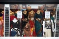 A sari seller peers out into a shop window with mannequins wearing saree