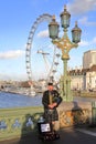 LONDON, UK - DECEMBER 31, 2015: Scottish musician playing bagpipes at sunset on Westminster Bridge with London Eye in the backgrou Royalty Free Stock Photo