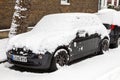 Street winter cityscape with snow covered frozen cars after a blizzard snowfall