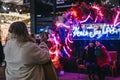 Woman taking a photo of friends in Spitalfields Market, London, UK, at dark, selective focus