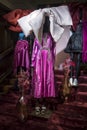 Black mannequins in a pink violet floral dress and a large beige bow and vase with dried flower in a window in a Liberty store on