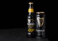 LONDON, UK - FEBRUARY 06, 2019: Bottle and aluminium cans of Guinness draught stout beer bottle on dark wooden background