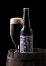 LONDON, UK - FEBRUARY 06, 2019: Bottle and glass of Jrt Black Heart stout beer, from the Brewdog brewery on old wooden barrel Royalty Free Stock Photo