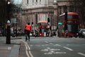 London UK February 2021 Cyclist wearing a red jacket waiting for the traffic lights on an intersection, double decker buses