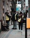 London UK February 2021 Three workers on the streets of London wearing yellow high visibility jackets on duty, one guy having a Royalty Free Stock Photo