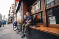 Food delivery driver sitting on the busy restaurant terrace in Soho area during Coronavirus lockdown ease