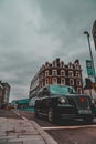 London UK January 2021 Iconic black London taxi waiting on a traffic sign stopped. Vertical wide angle shot, streets empty during