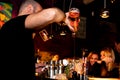 London, Uk - 20 january 2020: young bartender pour drink in glasses in spectacular and scenic way inside a bar at night with girls