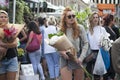 Red-haired girl in jeans shorts bought a bouquet of white hydrangea. Her friend is carrying a bouquet of orchids