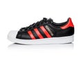 LONDON, UK - JUNE 05, 2019: Adidas Originals Superstar black shoe with red stripes on white background.German multinational