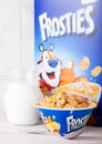 LONDON, UK - JUNE 01, 2018: Box of Kellogg`s Frosties Breakfast Cereal with milk and plate on white wood. Royalty Free Stock Photo