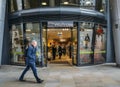 Officer worker walks past a Little Waitrose upmarket supermarket in Walbrook, City of London, England, UK