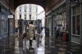 A classically dressed man in a gray cloak with an umbrella retires along the street