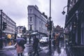Street scene in Covent Garden on a typical rainy day in London. People with umbrellas walking on the street. Royalty Free Stock Photo
