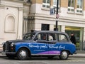 Traditional London taxi with advertisement banner parked at cab rank Royalty Free Stock Photo