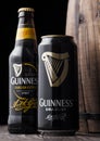 LONDON, UK - MAY 03, 2018: Aluminium can and glass bottle of Guinness draught stout beer next to wooden barrel on dark wooden back Royalty Free Stock Photo