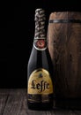LONDON, UK - MAY 03, 2018: Cold bottle of Leffe beer next to wooden barrel on black background.Leffe is made by Abbaye de Leffe in Royalty Free Stock Photo
