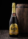 LONDON, UK - MAY 03, 2018: Cold bottle of Leffe beer next to wooden barrel on black background.Leffe is made by Abbaye de Leffe in Royalty Free Stock Photo