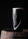 LONDON, UK - MAY 03, 2018: Original glass of Guinness draught stout beer on top of wooden barrel on dark wooden background. Royalty Free Stock Photo