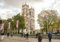 People walk on concrete walkway at Westminster Abbey decorated with national flag of United Kingdom