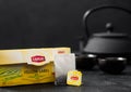 LONDON, UK - OCTOBER 21, 2020: Pack of Lipton Yellow Label black tea with tea bag and iron teapot on black