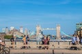 Pedestrians crossing London Bridge with Tower Bridge raised for ship to pass under in the background - some