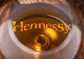 LONDON, UK - SEPTEMBER 04, 2018: Glass of Hennessy Cognac with original coaster on top of wooden barrel. Royalty Free Stock Photo