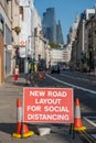 A red roadwork sign saying new road layout for social distancing with St Pauls at the end of the street in the background