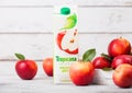 LONDON, UK - SEPTEMBER 13, 2018: Tropicana Apple Juice with fresh apples in box on wooden background.