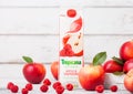 LONDON, UK - SEPTEMBER 13, 2018: Tropicana Apple and raspberry Juice with fresh apples in box on wooden background.