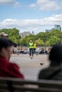 A view between out of focus heads of a man wearing a hi-visibility jacket on the South Bank of the River Thames