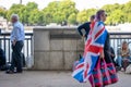 A woman wearing a Union Jack flag walks past a sign for The Queen's Walk and people queuing to see the Queen Lying in State Royalty Free Stock Photo