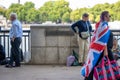 A woman wearing a Union Jack flag walks past a sign for The Queen's Walk and people queuing to see the Queen Lying in State Royalty Free Stock Photo