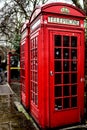 London UK - Traditional red British Telephone booths on sidewalk in Londonn on rainy winter day with a similar WIFI box