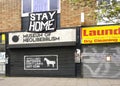 London, United Kingdom - April 03, 2020: Large STAY HOME sign above closed Museum of Neoliberalism in Lewsiham. Shops and museums