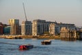 Skyline of new riverside apartment buildings with boats floating on the river Thames