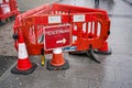 London, United Kingdom - February 04, 2019: Red roadblock with arrow sign directing pedestrians to walk around, placed on wet