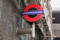 London, United Kingdom - February 01, 2019: Typical red and blue Underground sign at brick wall, construction scaffolding in