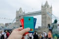 Revolut, Starling, Monzo bank cards hold in hand and London Tower Bridge at the blurred background. Conceptual: the competing fint