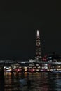 London, United Kingdom, March 24, 2024: Nighttime Cityscape with Illuminated Skyscraper and Bridge over River