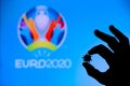 LONDON, UNITED KINGDOM - MAY 25, 2020: Hands silhouette holds covid 19 virus, logo of summer football tournament Euro 2020 in