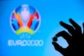 LONDON, UNITED KINGDOM - MAY 25, 2020: Hands silhouette holds covid 19 virus, logo of summer football tournament Euro 2020 in