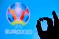 LONDON, UNITED KINGDOM - MAY 25, 2020: Hands silhouette holds covid 19 virus, logo of summer football tournament Euro 2020 in