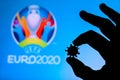 LONDON, UNITED KINGDOM - MAY 25, 2020: Hands silhouette holds covid 19 virus, logo of summer football tournament Euro 2020 in