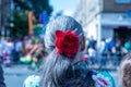 Back view of a senior female with a red flower hairband at the Hackney Carnival in London, UK