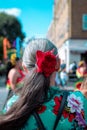 Back view of a senior female with a red flower hairband at the Hackney Carnival in London, UK